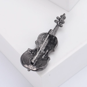 Close-up of violin brooch back showing secure metal pin fastening and vintage texture
