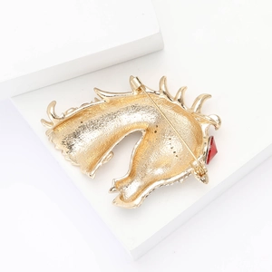Macro view of the golden horse head brooch back with needle clasp and red gemstone detail