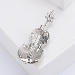 Detailed view of the silver violin brooch back with pin clasp and alloy metal texture