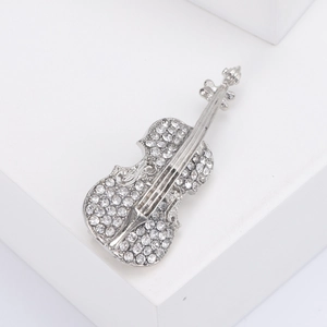 Silver violin brooch with sparkling rhinestones on a minimalist white background