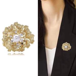 Detailed view of floral gold brooch with pearl and crystal rhinestones on a black blazer