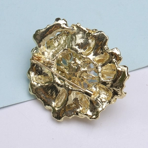 Detailed back view of a golden floral brooch showing the secure metal pin and alloy texture