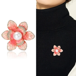 Close-up and styling of enamel flower brooch with pink petals and a center pearl