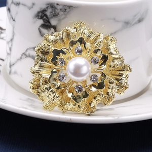 Macro shot of gold floral brooch featuring white faux pearl and crystal rhinestones