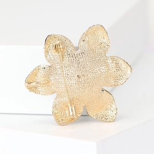 Elegant gold flower brooch back view showing secure needle clasp and textured metal