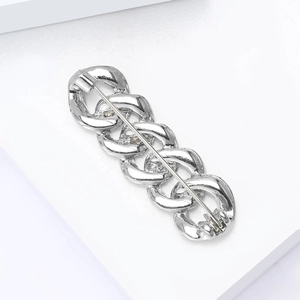 Detailed view of silver alloy chain brooch with interlocking rings and long pin closure
