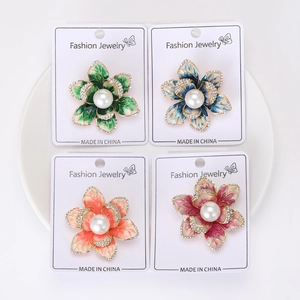 Detailed view of four enamel flower brooches with central pearls and crystal edges