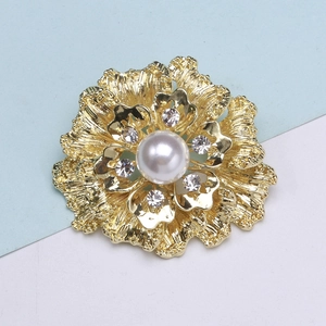 Close-up of golden flower brooch with large pearl and sparkling crystal rhinestones
