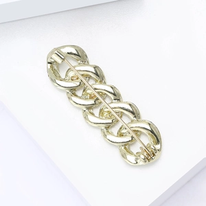 Detailed view of the gold chain brooch with polished metallic rings and secure pin back