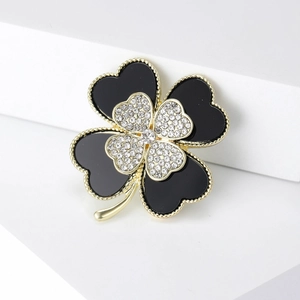 Detail of four-leaf clover brooch with black enamel, white rhinestones and golden metal trim