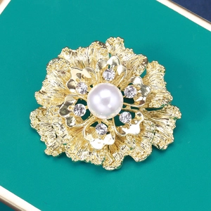 Macro shot of gold flower brooch with central pearl and sparkling rhinestones