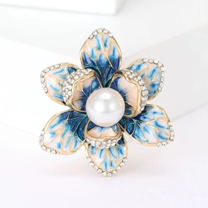 Detail of flower brooch with blue enamel petals, white rhinestones and a central pearl