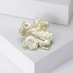 Detailed back view of gold clover brooch featuring safety pin clasp and textured finish