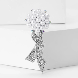 Detail shot of a refined bouquet brooch with pearls and colorful rhinestones on a white stand