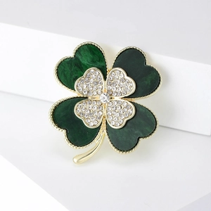 Close-up of green clover brooch with sparkling rhinestones and golden beaded edges