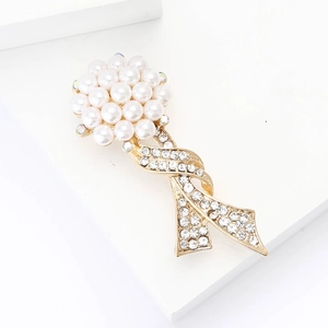 Elegant gold alloy floral brooch featuring white pearls and sparkling rhinestone ribbons