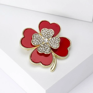 Detailed view of a red four-leaf clover brooch with gold trim and sparkling rhinestones