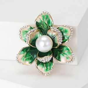 Detailed close-up of a floral enamel brooch featuring white pearls and green gradient leaves