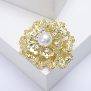 Elegant gold flower brooch with white pearl and rhinestones on geometric display