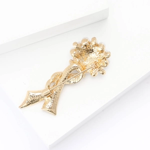 Macro view of gold floral ribbon brooch showing secure pin fastener back detail