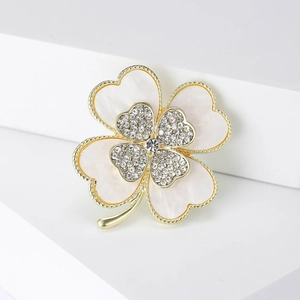 Macro view showing double-layered clover brooch with white crystals and mother-of-pearl