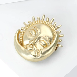 Gros plan détaillé de la broche soleil et lune en or mat au design mythique céleste