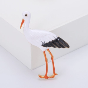 Broche grue élégante avec émail blanc et détails dorés sur un socle d'exposition