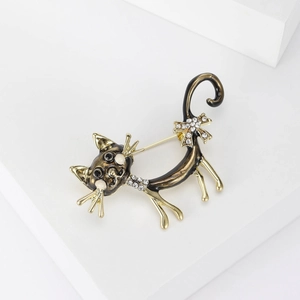 Detail of a black enamel cat brooch with rhinestone collar and bow on a white stand