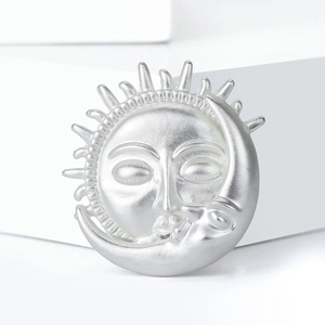 Broche soleil et lune en argent mat avec design céleste sur support blanc moderne
