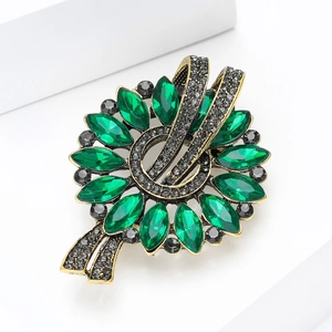 Macro shot of vintage marquette brooch with emerald stones and antique gold finish