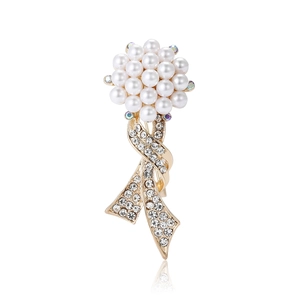 Elegant gold bouquet brooch with white pearls and sparkling rhinestones on white base