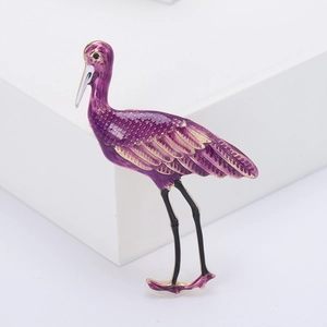 Vue détaillée d'une broche oiseau en émail violet avec des détails dorés sur fond blanc