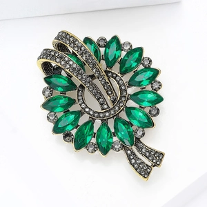 Macro detail of vintage emerald eye brooch with antique gold finish and small grey rhinestones