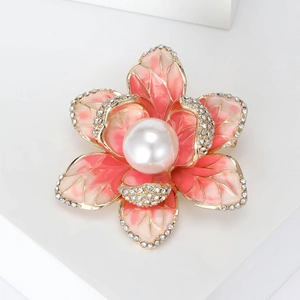 Detailed close-up of enamel flower brooch with sparkling rhinestones and a white pearl