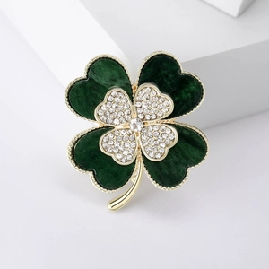 Elegant gold-tone four-leaf clover brooch with green enamel and sparkling rhinestones