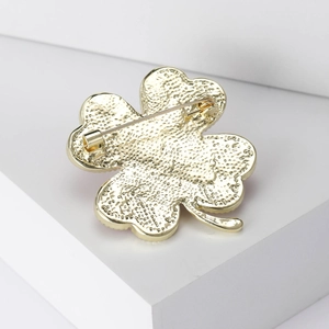 Back view of a gold four-leaf clover brooch showing detailed matte texture and pin clasp