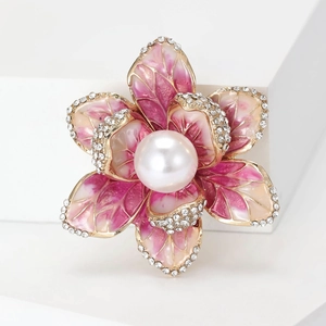 Detailed close-up of enamel flower brooch with pink petals, crystal edges and pearl center