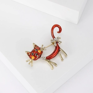 Close-up of red enamel cat brooch with gold finish and sparkling crystal bow accents