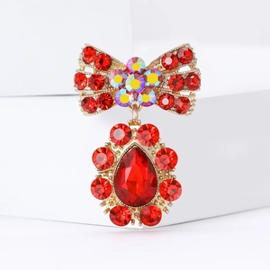 Élégante broche nœud doré avec strass rouges et un pendentif en rubis en forme de poire