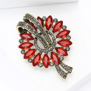 Macro detail of antique gold brooch with marquise-cut red gems and ribbon design