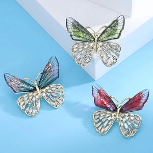 Macro detail of butterfly brooches with gradient enamel wings and crystal inlay