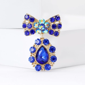 Détail de la broche nœud doré avec strass bleus et pendentif en forme de goutte
