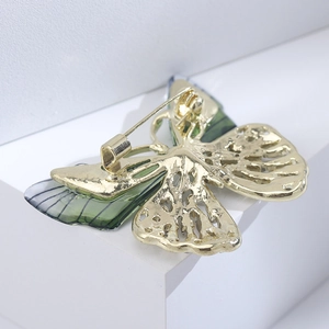 Detailed back view of a butterfly brooch showing the secure pin clasp and gold metal base