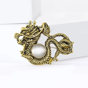 Detailed macro view of golden dragon brooch with polished scales and opal center stone