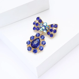 Vue détaillée d'une broche nœud dorée avec strass bleus et gemme en forme de poire