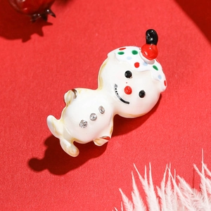 Broche bonhomme de neige en émail blanc avec strass sur un fond rouge de fête