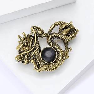 Detailed view of a vintage gold dragon brooch with a black cat eye stone on a suit lapel