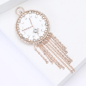 Detail of rose gold enamel clock brooch with tassel chains and sparkling rhinestones