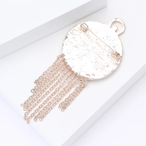 Detailed close-up of rose gold enamel clock brooch with elegant dangling metal tassels