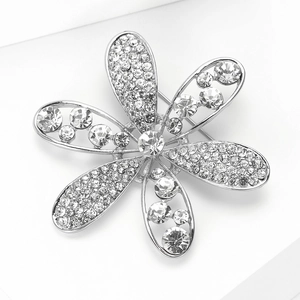 Gros plan d'une broche fleur argentée avec strass blancs et détail de l'épingle